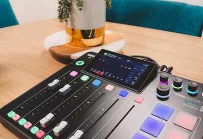 Audio mixing console on a wooden table next to a potted plant.