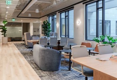 Bright coworking area with a mix of soft seating, dining tables, and large windows.
