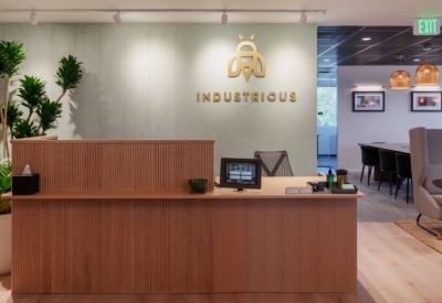 Warm reception area with a wood-slat desk, branded wall, and indoor plants.