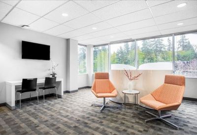 Modern lounge area with stylish orange armchairs and a small workstation desk.