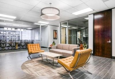 Modern lounge area with tan leather Barcelona chairs and a grey sofa.