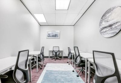 Bright shared workspace with white desks and ergonomic chairs on a purple carpet.