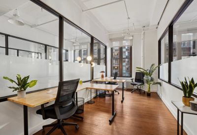 Internal two-person office suite with glass partitions and blonde wood desks.