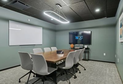 Sleek meeting room with a large wooden table, grey chairs, and a dark grey ceiling.