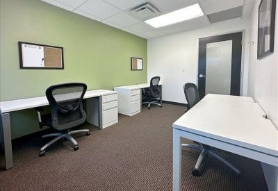 Contemporary lounge area with tan armchairs and a sleek curved partition.