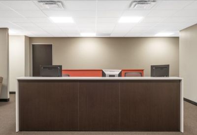 Sleek dark wood reception desk with a white countertop in an open lobby area.