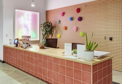 Modern reception desk with pink tiling, a pegboard feature wall, and colorful decor.