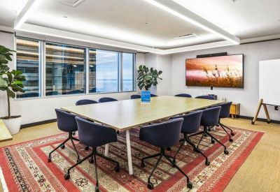 Professional meeting room with a large light-wood table, navy chairs, and a colorful area rug.