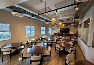 Spacious dining area with dark wood tables, white upholstered chairs, and industrial track lighting.