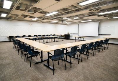Large classroom-style meeting room with a U-shaped table layout and a projector screen.