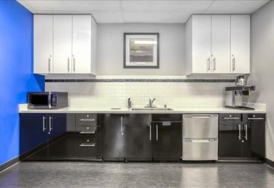 Contemporary breakroom kitchen with sleek black cabinetry and a blue accent wall.