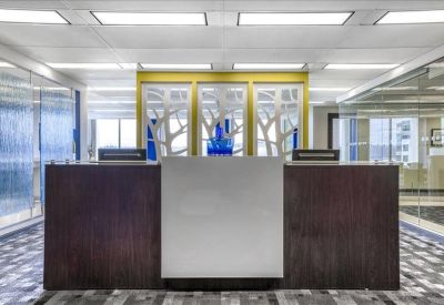 Bright reception desk with dark wood paneling and a decorative glass background.