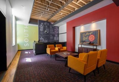 Spacious reception area with orange armchairs and a red feature wall.