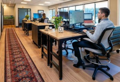 Collaborative coworking area with multiple workstations and a patterned rug runner.