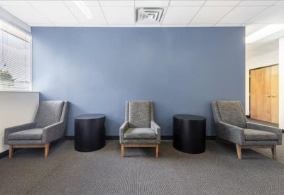 Waiting area featuring grey armchairs against a blue feature wall.