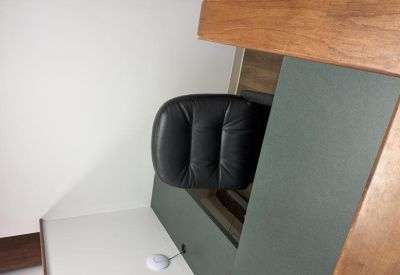 Close-up of a modern workstation featuring a black leather chair and a dark desktop.