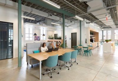 Spacious communal lounge with a large wooden table and teal armchairs.