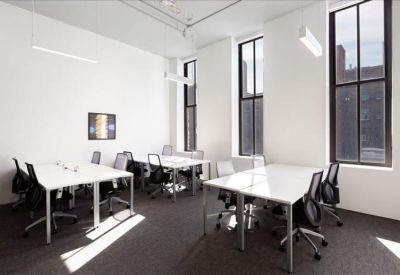 Bright, white office with several individual desks and tall windows.