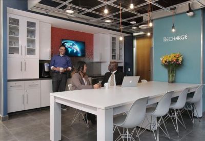 Modern communal break area with a white dining table and colorful accent wall.