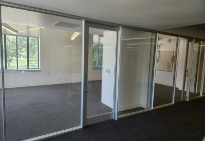 Glass-walled meeting room overlooking an open-plan office area.