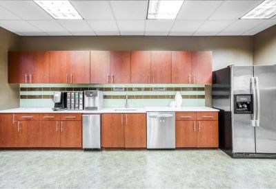 Contemporary breakroom kitchen featuring wood cabinetry, tiled backsplash, and stainless steel appliances.
