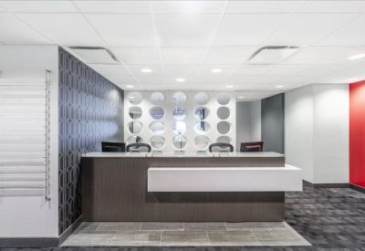 Modern reception area featuring a dark wood desk with a white tiered front and patterned feature wall.