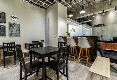 Communal break area with small tables, chairs, and a bar counter next to the reception.