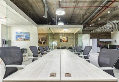 Bright, industrial-style conference room with a long white table and mesh office chairs.
