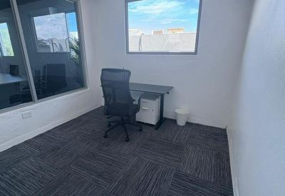 Internal office suite featuring a black desk, filing cabinet and large interior window.