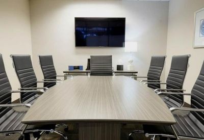 Symmetrical boardroom setup with black leather chairs facing a large TV screen.