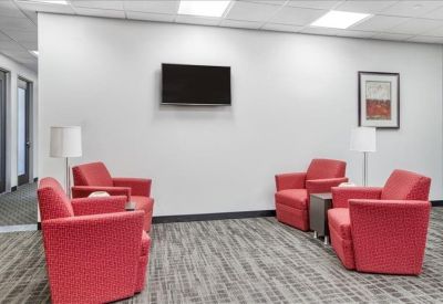 Lounge area featuring four red armchairs and a wall-mounted television.