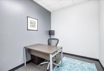 Small private office with a single desk, ergonomic chair, and framed wall art.