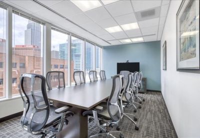 Spacious boardroom with a large dark wood table, mesh chairs, and city views.