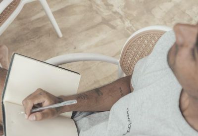 Worker taking notes in a notebook on a bright outdoor terrace.