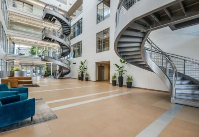 Spacious, modern lobby at 130, East John W Carpenter Freeway, Suite 220 featuring dramatic spiral staircases and plants.