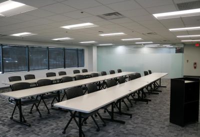 Large training room with rows of long white tables and black mesh chairs.