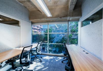 Private two-person office with large windows and lush greenery outside.
