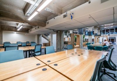 Open-plan workspace with light wood desks and industrial concrete ceilings.