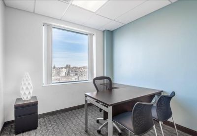 Private office with a blue feature wall and a desk overlooking the city.