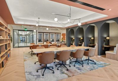 Spacious coworking area with a long wooden table, leather chairs, and arched study nooks.