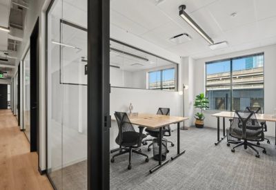 Private office suite with two wooden desks, ergonomic black chairs, and large window views.