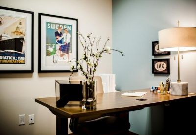 Sunlit private office featuring two framed posters and a dark wood desk.