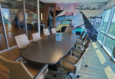 Modern conference room with an oval table and large windows overlooking greenery.