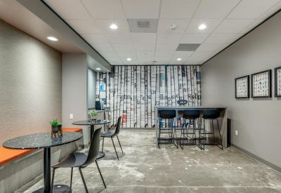 Modern breakout area with round cafe tables and a birch tree forest feature wall.