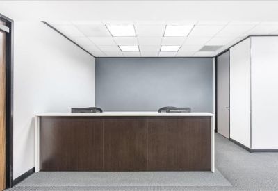Professional reception area with a dark wood front desk and grey accent wall.