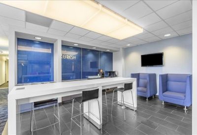 Communal break area featuring a high white bar table and blue high-back lounge chairs.