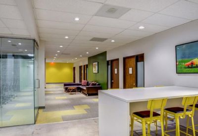 Communal break area with a white high-top table and bright yellow bar stools.