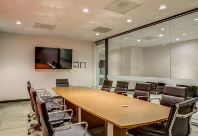 Professional conference room with a large wooden table and black leather chairs.