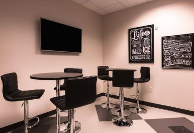 Breakroom seating area with high-top tables, bar stools, and decorative chalkboard art.