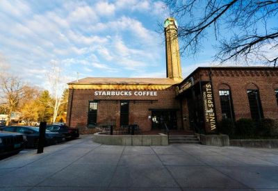 Brick commercial building featuring a Starbucks storefront and an industrial-style clock tower.